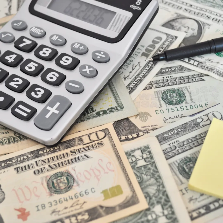 A calculator and scattered U.S. dollar bills illustrating roofing financing and cost management options.