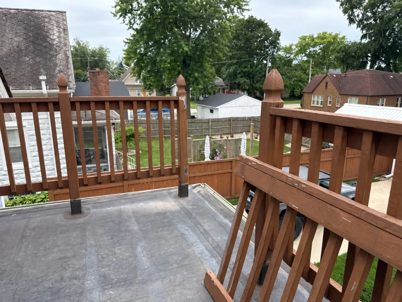 Balcony before restoration in Plainfield, IL, showing the exposed flat roof surface and older wood railing.