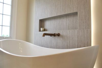 Freestanding bathtub with textured accent wall and built-in shelf