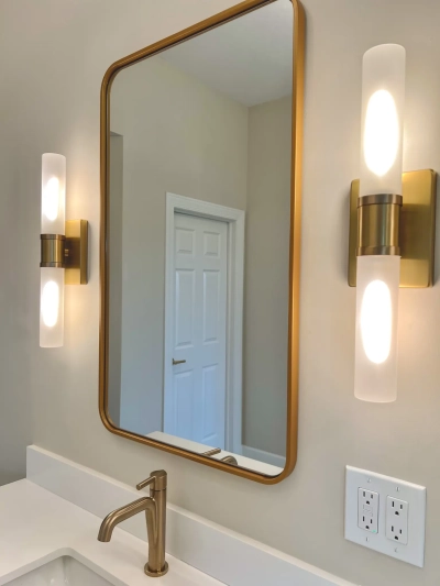 Gold-framed bathroom mirror with wall-mounted sconces