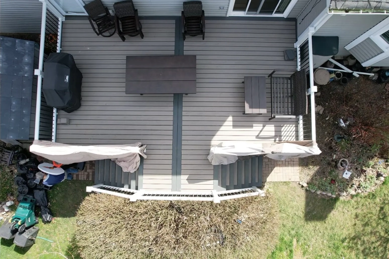Aerial view of gray composite deck with dining furniture and grill installed by Lombard IL deck contractor