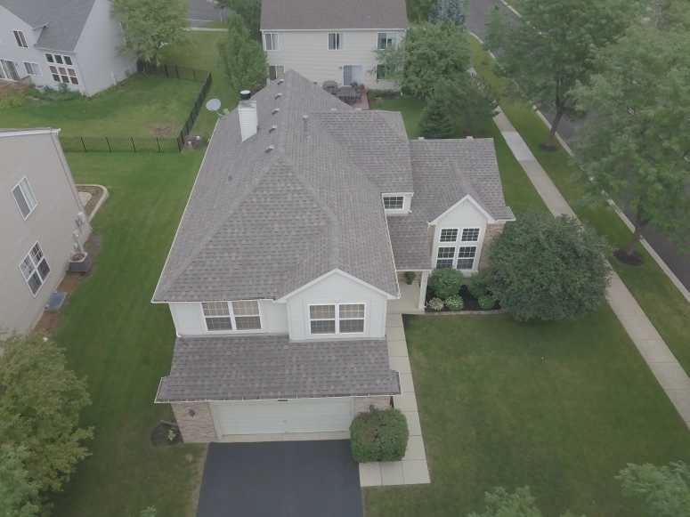 Aerial view of completed asphalt shingle roof replacement on two-story suburban home in Aurora Illinois