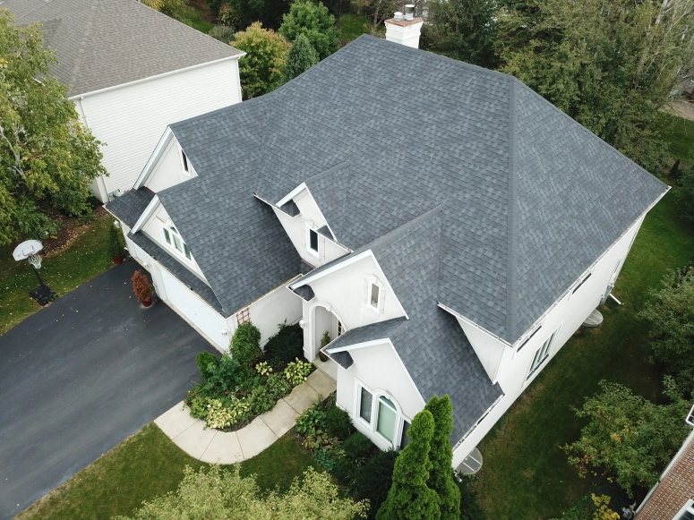 Aerial view of new charcoal asphalt shingle roof replacement on large two-story home in Geneva IL