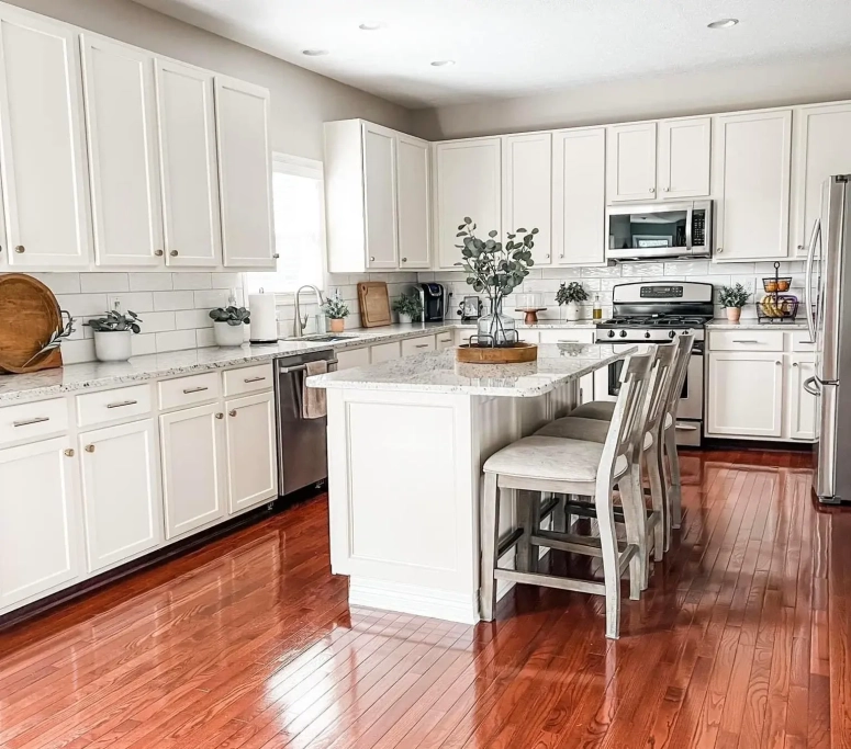 White raised panel kitchen cabinets with granite countertops and island seating after cabinet resurfacing