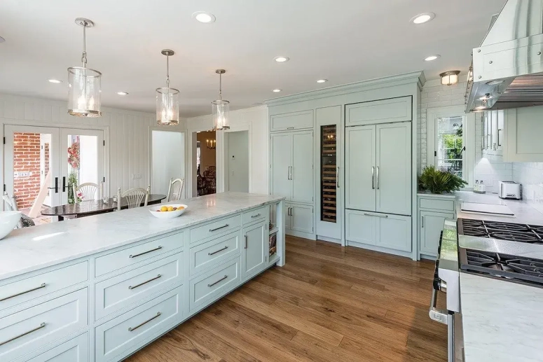 Light blue shaker cabinets with marble countertops and wine fridge in a resurfaced kitchen