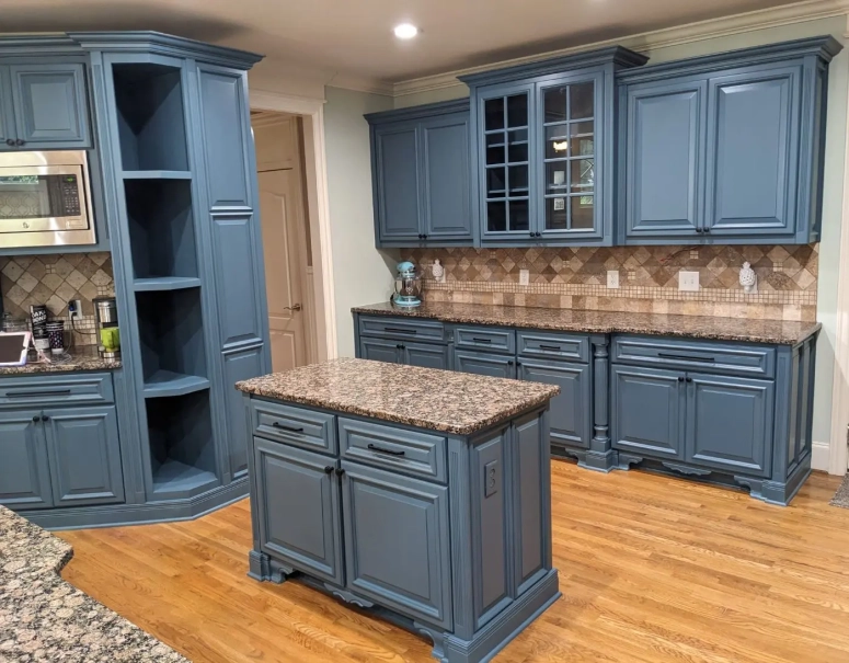 Navy blue raised panel kitchen cabinets with granite countertops and decorative corner shelving after cabinet resurface
